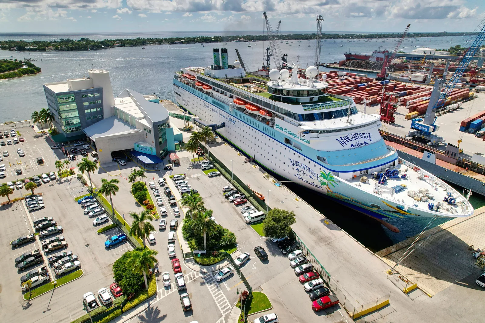 Aerial photograph of the Port of Palm Beach cruise terminal with Margaritaville at Sea Paradise berthed alongside and the passenger self-parking lot in the foreground