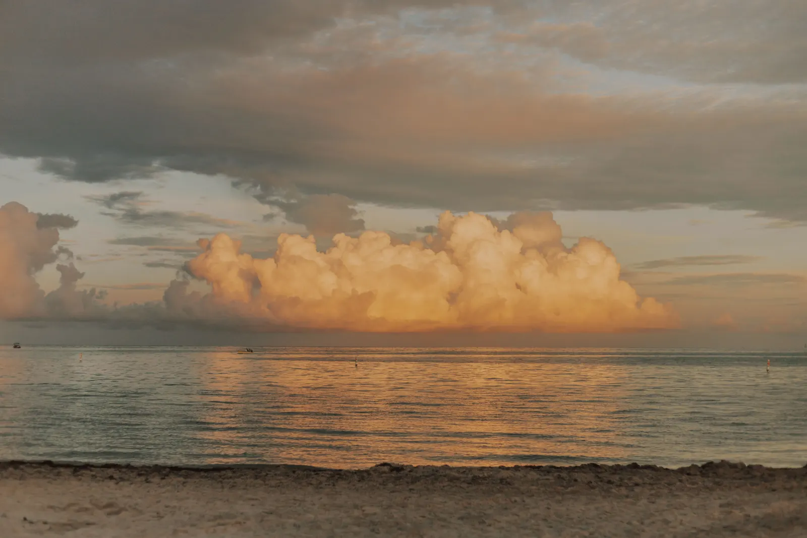 Tranquil beach sunset at Key West with golden clouds reflecting on calm waters.