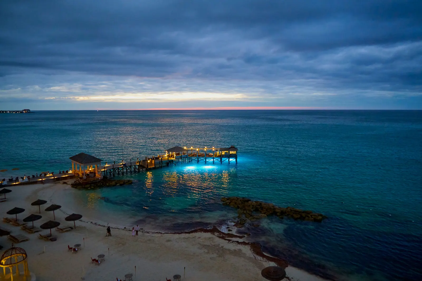 Twilight envelops the serene beach and pier in Nassau, The Bahamas, with stunning seascape views.