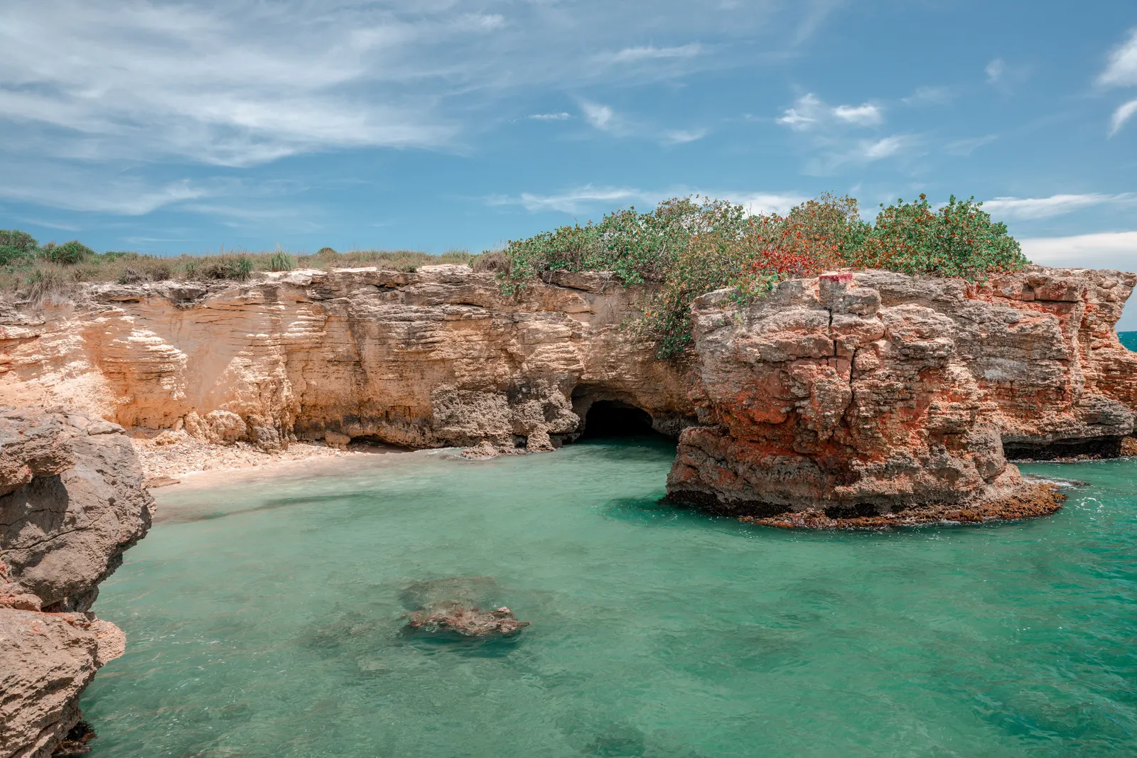 Explore the stunning coastal rock formations and turquoise waters of Cabo Rojo, Puerto Rico under a bright summer sky.