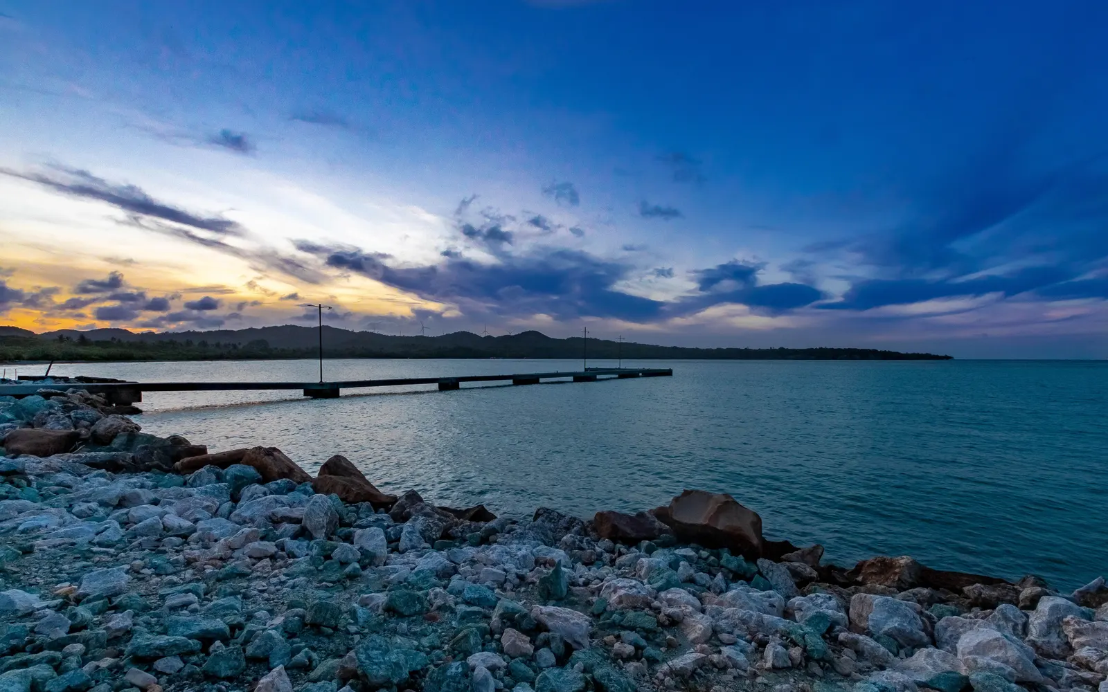 Dramatic evening sky over a rocky shoreline and pier in Puerto Plata, Dominican Republic.